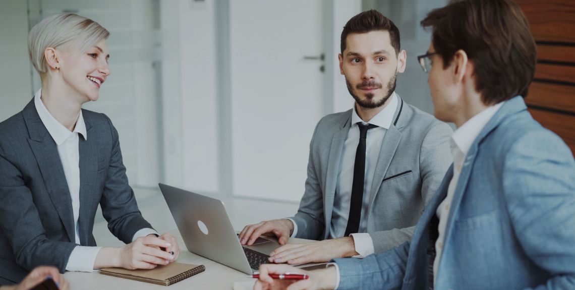 Drei Teammitglieder sitzen in einer Besprechung am Tisch Drei Teammitglieder sitzen in einer Besprechung am Tisch